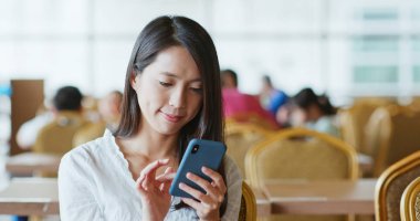 Kahve dükkanında cep telefonu kullanan kadın