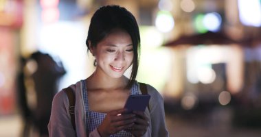 Şehirde akşam cep telefonu kullanan kadın