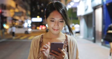 Smartphone şehirde geceleri kullanan kadın