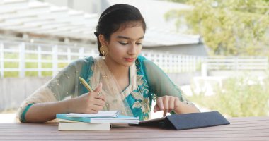 Genç Pakistan kız çalışma tablet ve kitap yazma 