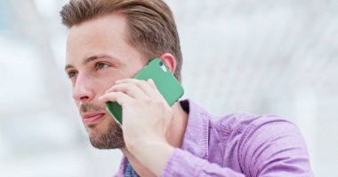 şehir içinde cep telefonu üzerinde konuşan adam