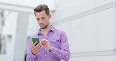 Şehirde cep telefonu kullanan genç adam.