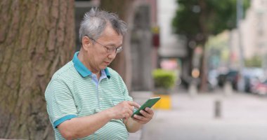 Asyalı yaşlı adam cep telefonuyla, açık