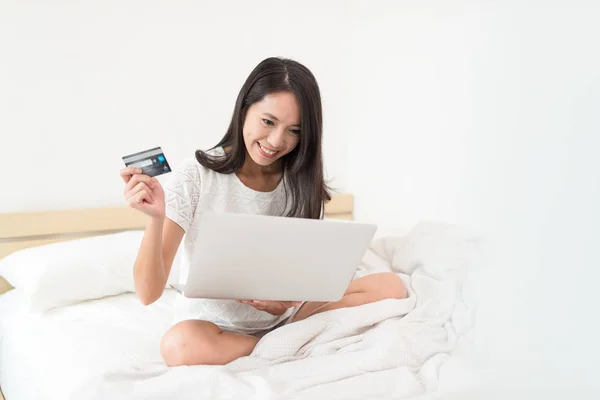 妇女支付信用卡与笔记本电脑在床上 — 图库照片