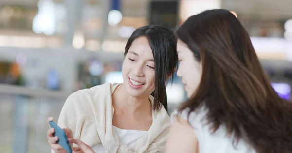 Friends chatting with cellphone in airport