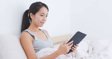 yatağın üzerine tablet bilgisayar kullanan kadın