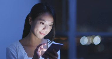 Akşamları evde akıllı telefon kullanan kadın