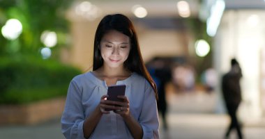 Gece şehirde akıllı telefon kullanan bir kadın.