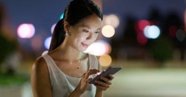 Kadın geceleri cep telefonunu kontrol ediyor.