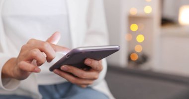 Evde cep telefonu kullanan bir kadın