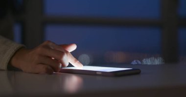 Geceleri cep telefonu kullanan bir kadın.