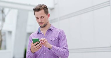 Şehirde cep telefonu kullanan genç adam.