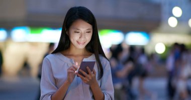 Kadın geceleri cep telefonunu kontrol ediyor.