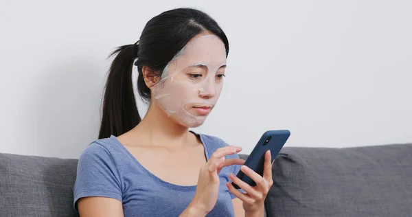 Vrouw Met Behulp Van Mobiele Telefoon Papier Masker Toepassen Gezicht — Stockfoto