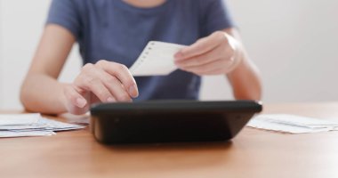 Kadın evde hesap makinesi üzerinde günlük harcama hesaplama