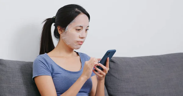 Vrouw Met Behulp Van Mobiele Telefoon Papier Masker Toepassen Gezicht — Stockfoto