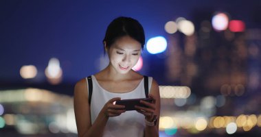 Kadın oynamak oyun cellphone şehir içinde geceleri