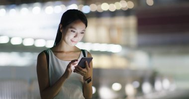 Asyalı kadın cep telefonuyla şehirde geceleri