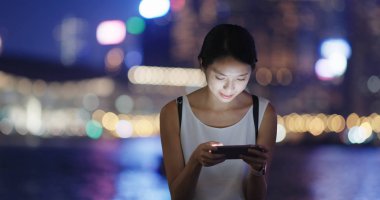 Kadın oynamak oyun cellphone şehir içinde geceleri