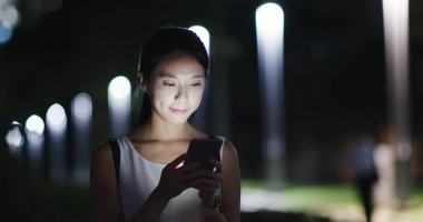 Asyalı kadın cep telefonuyla şehirde geceleri