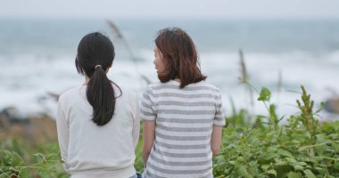 Arkadan sohbet ve deniz kenarında oturan genç kadınların arka görünüm