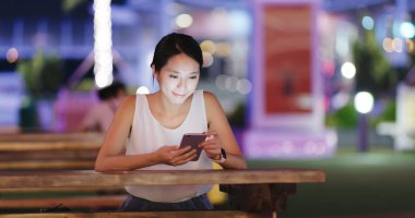 Cep telefonu açık kahve dükkanında geceleri kullanan kadın