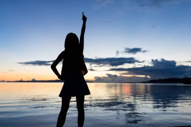 Gündoğumu zaman deniz ile duran kadın silüeti