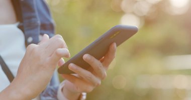 Gün batımı ile şehirde cep telefonu kullanan kadın