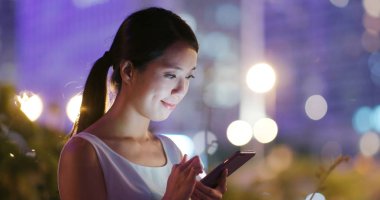 Kadın geceleri şehir içinde hareket eden telefon bakmak