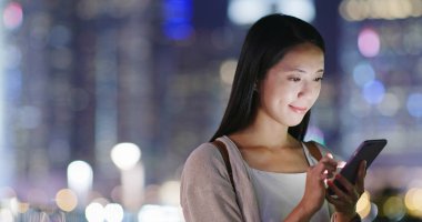 Geceleri cep telefonu kullanan bir kadın.