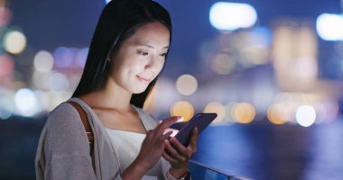 Geceleri cep telefonu kullanan bir kadın.