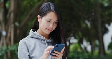 Cep telefonu kullanan kadın ve şehir parkta oturmak