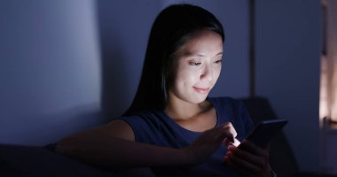 Evde akıllı telefon kullanan bir kadın.