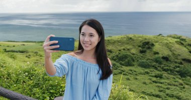 Kadını Ishigaki Adası landmark cep telefonunda selfie kabul