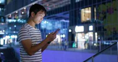 Smartphone şehirde geceleri kullanan adam