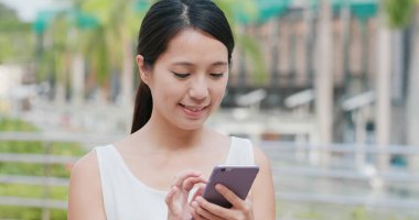 Kadın dışarıda cep telefonuyla çalışıyor.