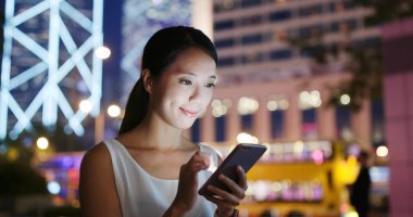 Şehirde akıllı telefon kullanan bir kadın