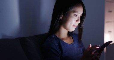 Evde cep telefonu kullanan bir kadın