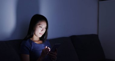 Geceleri cep telefonu kullanan bir kadın.