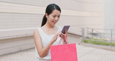 Alışveriş çantası ve cep telefonu kullanımı tutan kadın