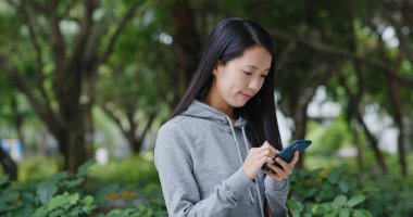 Cep telefonu kullanan kadın ve şehir parkta oturmak