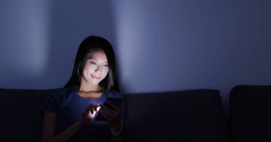 Evde cep telefonu kullanan bir kadın