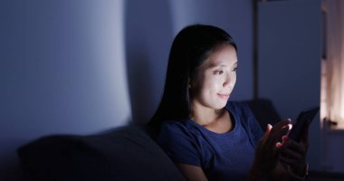 Evde cep telefonu kullanan bir kadın