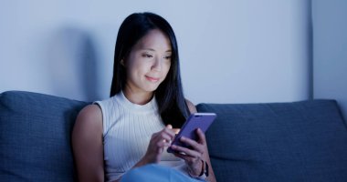 Evde cep telefonu kullanan bir kadın