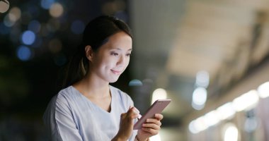 Kadın geceleri cep telefonuyla çalışıyor.