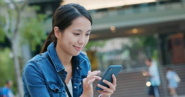 Şehirde akıllı telefon kullanan bir kadın