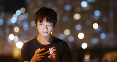 Geceleri cep telefonu kullanan adam.