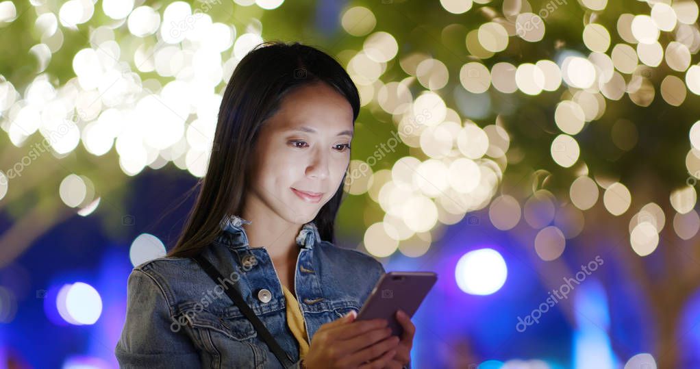 Woman use of mobile phone in city at night