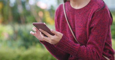 Parkta akıllı telefon kullanan kadın.