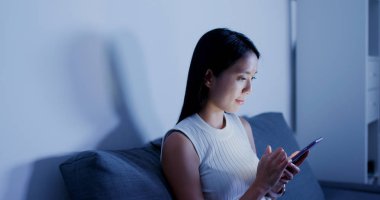 Evde cep telefonu kullanan bir kadın